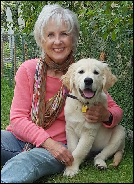 Woman sitting on lawn with Golden Retriever puppy